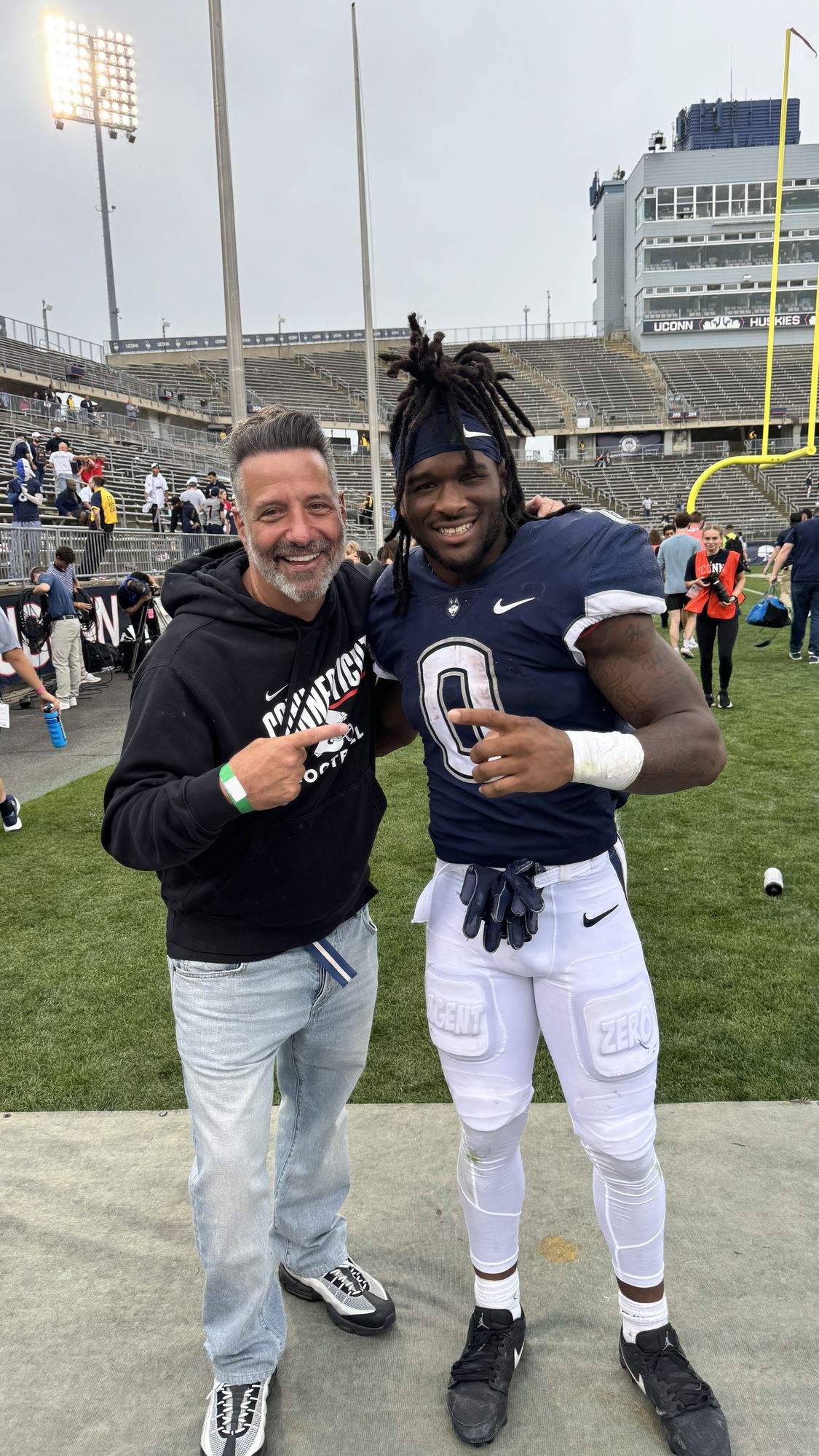 Marc D'Amelio with a UConn Football player on the field at Pratt & Whitney Stadium